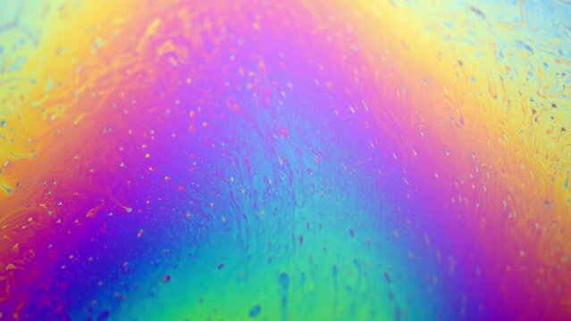 Close-up macro of colorful iridescent moving soap film surface, vibrant rainbow colored pattern and texture background