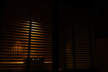 Close-up of blinds in the dark. Abstract background.This blinds is brown on the yellow background. Perspective angle of the Venetian or wooden blinds.