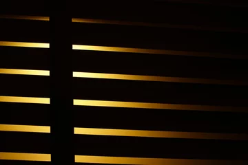 Poster Im Rahmen Close-up of blinds in the dark. Abstract background.This blinds is brown on the yellow background. Perspective angle of the Venetian or wooden blinds. © Apicha