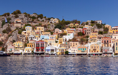Fototapeta na wymiar Colorful traditional multi-colored houses on the shore of the bay on Symi island.