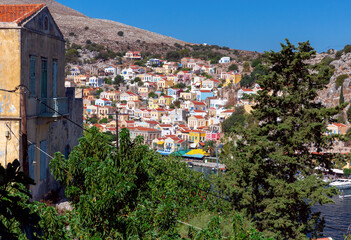 Obraz premium Colorful traditional multi-colored houses on the shore of the bay on Symi island.