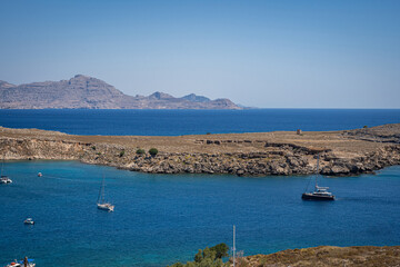 Enchanting Bay in Lindos, Rhodes: A serene Mediterranean retreat where moored boats meet the captivating turquoise embrace of the sea.