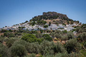 Distant View of Lindos on Rhodes Island: A Grecian tapestry of sunlit whitewashed buildings, all...
