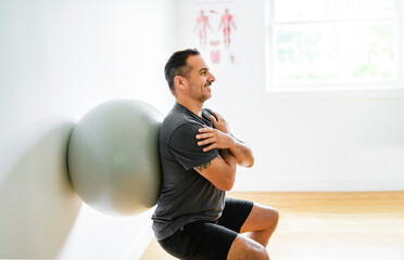 Modern rehabilitation client using ball on physiotherapy place