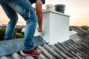 Worker applying white seamless concrete pebble-dash plaster on chimney using putty knife.