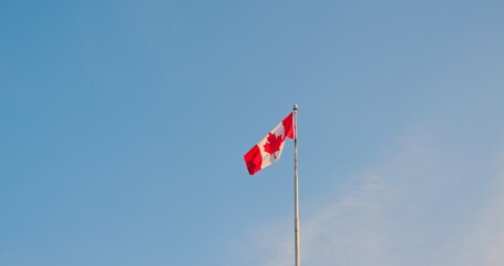 National flag of Canada also known as The Maple Leaf. Red white flag of Canada fluttering in breeze. Slow motion bottom view of Canadian flag high in sky. Enjoy atmosphere of Canada and Canadian life