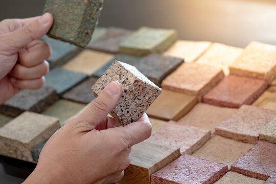 Designer hand comparing samples of sustainable decoration material made from rice straw. Natural texture and pattern for interior finishing design or building facade. Alternative material from nature