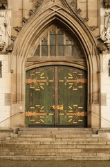 an old stone building has green doors and ornate designs on it