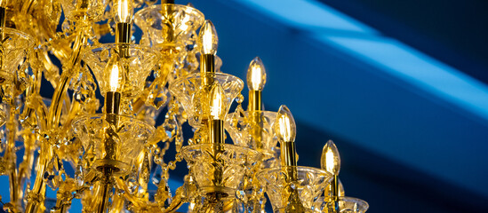 Close up of golden crystal chandeliers lamp hanging in a blue room. Lighting design for luxury...