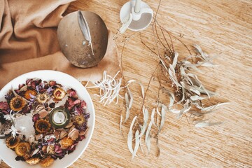 Closeup of a  wooden table with a bowl of assorted dried flowers  under the natural light