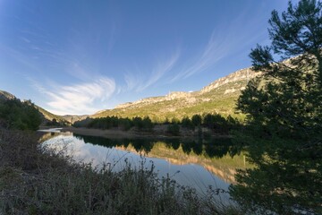 Scenic view of a river in green mountains on a sunny day in Buendia, Cuenca