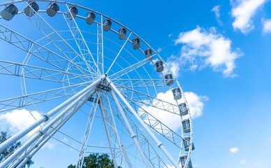 Obraz premium Big, tall white Ferris wheel in front of a perfect blue sky