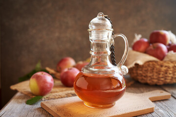 A bottle of apple cider vinegar with fresh apples
