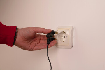 Different standards for electrical outlets. Unsuitable connector and plug in the hand of a person....