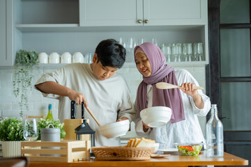 Cute son And His Muslim Mom In Hijab Preparing Pastry For Cookies In Kitchen, Baking Together At Home. Islamic Lady With son Enjoying Doing Homemade Pastry, preparing to cook breakfast for her family.