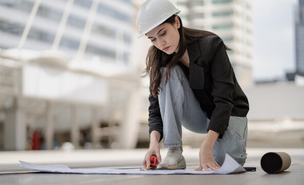 Estate architect working on real estate structure development in urban. Female property development engineer reading blueprint and plan skyscraper layout. Beautiful woman designer analyzing project.