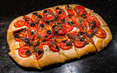 Fresh homemade pizza in rectangle shape with beef,  buffalo mozzarella, tomatoes and olive.