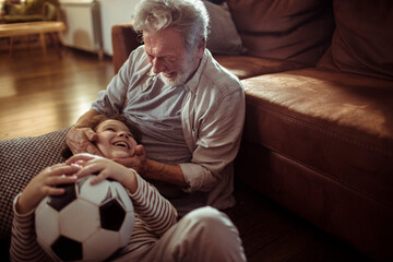 Happy grandfather playing with his grandson at home