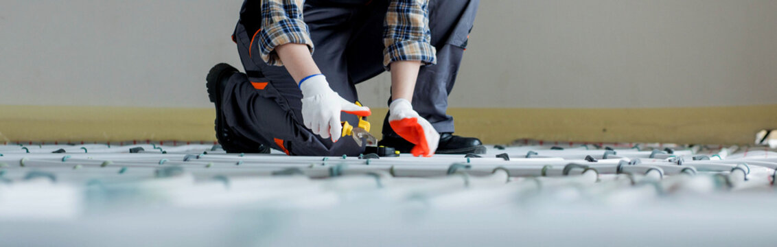 Woman worker is installing underfloor heating system. Warm floor heating system