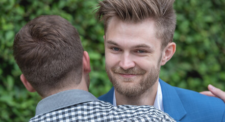 Fototapeta premium Happy couple gay holding hands looking to each other in the park. Lgbt lover man homosexual gay hug together.