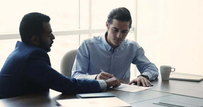 Male client buy company services, put signature on document accept agreement terms, approve contract conditions shake hands express respect for cooperation, congratulate with successful deal. Business