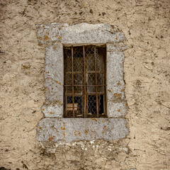 Window in a stone frame behind a metal grille