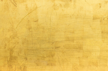 Artificial Gold background and texture on cement make from color paint for look like real gold. Gold foil leaf dirty abstract background texture distress scratch and gradients shadow in Gold glitter