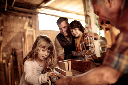 Young future carpenters learning the ways of their elders in a wood shop - Powered by Adobe