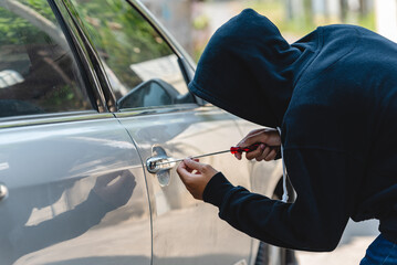 Car thief with mask steal robber trying to open car door by screwdriver . Thieves try to breaking window car door at danger car parking vandalism looting.