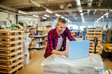 Young man using a laptop while working in a warehouse