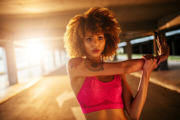 Young fit woman stretching before jogging under a bridge in the city