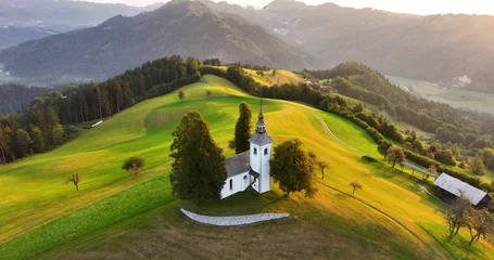 Fotobehang Aerial view of St. Thomas church on top of a hill, sunrise, Skofja Loka, Slovenia © Vgallery