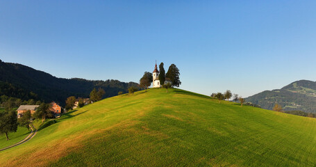 St. Thomas church in Skofja Loka, Slovenia, aerial view at sunrise golden hour