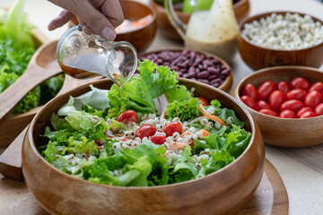 Hand chef mix fresh baby cos salad millet Crab Stick and pour salad dressing in wood blow. Organic Vegetables mix lunch with green salad In bowl. Breakfast fresh salad and clean vegetable