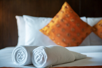 Soft pillows and white towel on clean white bed. Pillows bed with bedding sheets in bedroom. Bed sheets and pillows messed. Hotel, resort or home can relax on bed for deep sleep.