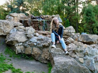 Natural Curly Blonde Woman, Albino Sitting in park, Outdoors. Lack of melanin pigment in hair and skin. A person with poor eyesight wearing glasses. Vertical