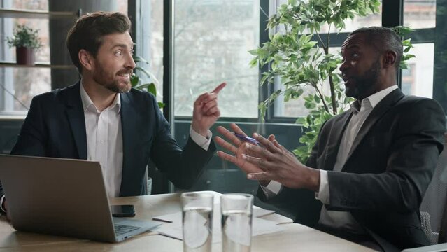 Two diverse business men talking laughing fun at office meeting African and Caucasian businessmen talk multiracial colleagues joking laugh in friendly coworking with laptop partnership friends at work