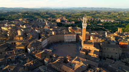 Aerial view of Torre del Mangia (Mangia Tower) in Piazza del Campo (Campo Square) in Siena, Tuscany, Italy. Drone orbit shot at sunset