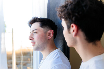 Gay couple sharing a special moment or having an argument in the morning by the window. Homosexual life routine.