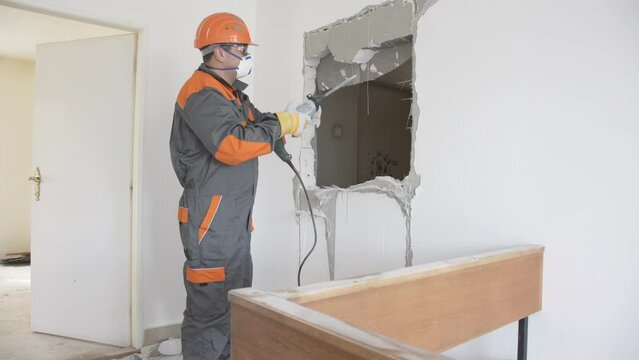 Builder Professional Worker With Electric Drill demolition or destruction  hammer, constructions door hole in wall