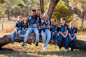 Happy big Australian family sitting together on log