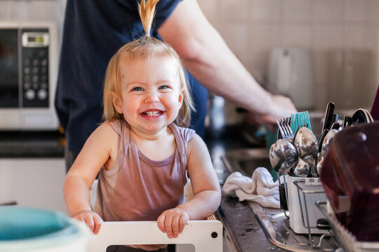 grinning baby wet from helping wash dishes in kitchen sink