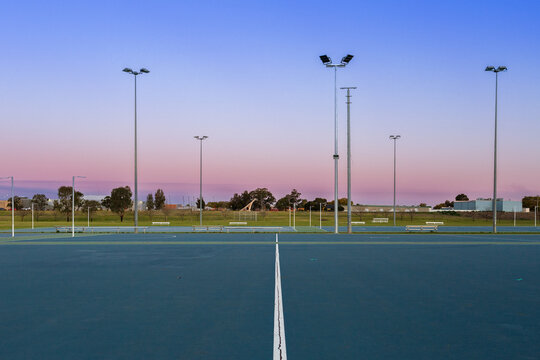 Dusk sky behind empty netball courts in sports park