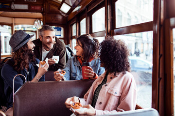 Young group of diverse friends eating snacks on a retro tram in the city