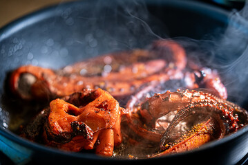 Cooking tentacles of octopus in frying pan.
