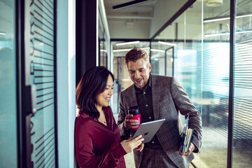 Two diverse colleagues using a tablet together in a modern office