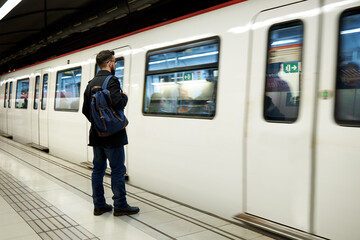 Young man standing in front of subway train