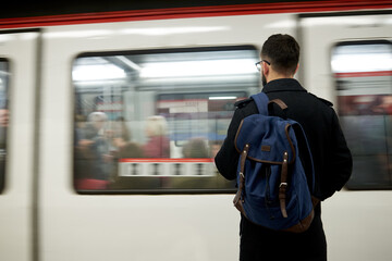 Young man standing in front of subway train