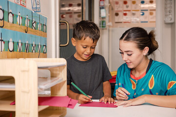 Young boy writing with educator