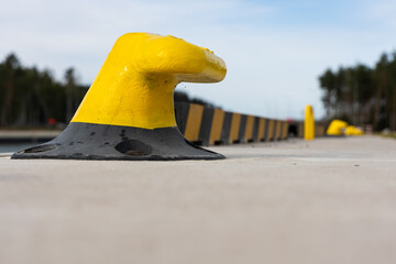 Yellow mooring hook on the concrete quay. Safety of boats moored to the waterfront. Photo taken on...